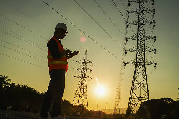 istock High Voltage Tower and Power Lines with Engineer Silhouette at Golden Hour 2252210847