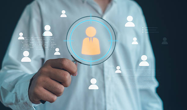 istock person holding a magnifying glass focusing on a target user icon, representing customer targeting, audience analysis, recruitment selection, data-driven strategies for identifying ideal individuals. 2252212969