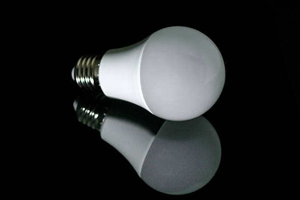 Studio shot of LED light bulb positioned against dark magenta gradient background. Represents creative idea, energy conservation and technology advancement in minimalist composition.