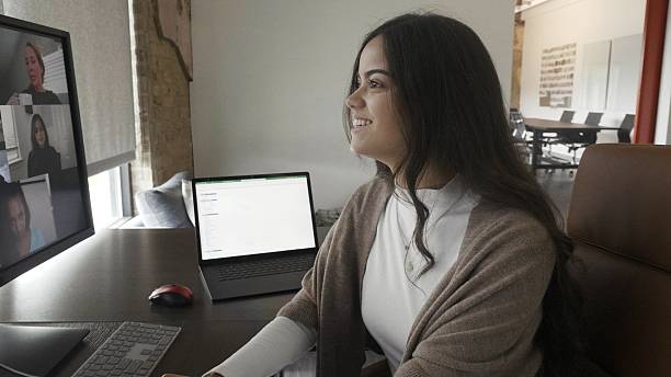 istock Young woman smiles during a virtual meeting with colleagues on a computer screen. 2252214703