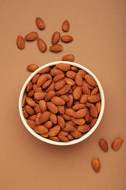istock Almonds in bowl on brown background. Whole and dried nuts. Vertical photo 2252215773