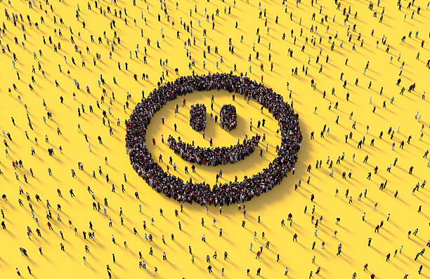 Human crowd forming a smiley face emoji on yellow background.