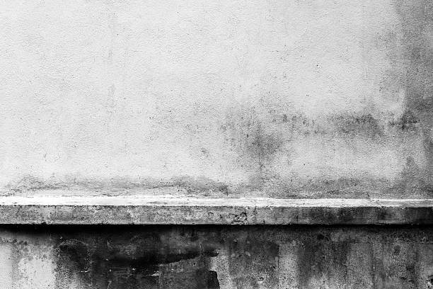 istock Textured concrete wall with black stains and horizontal ledge 2252229595