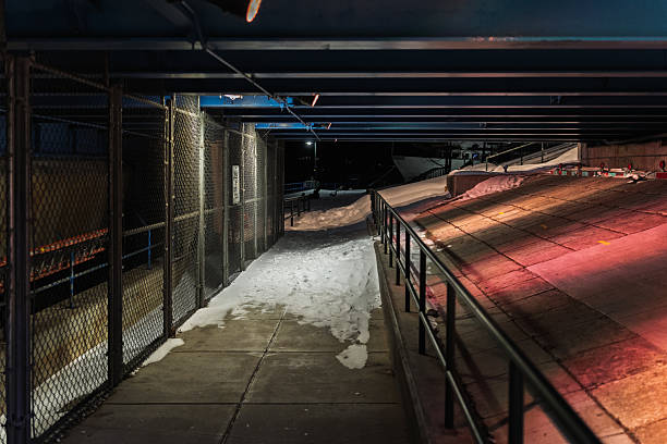 A dimly lit hallway with a red and blue light illuminating the ground. The hallway is empty and the light casts a warm glow on the snow-covered ground
