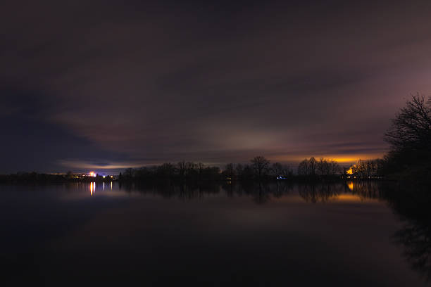 Cloudy night sky above pond, Czech landscape. Long exposure