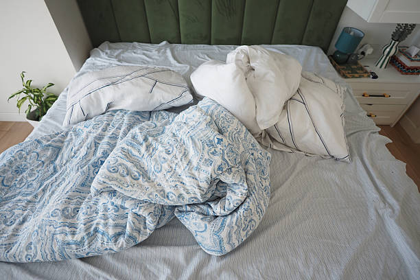 istock Cozy unmade bed with wrinkled linens and pillows 2252234301