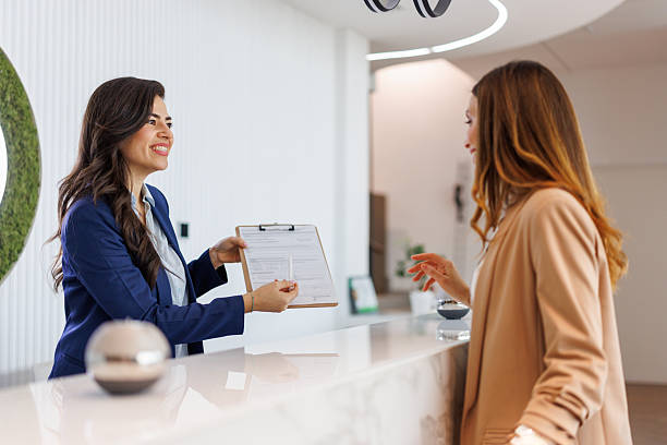 istock Receptionist assisting client with check-in paperwork at modern desk 2252237576