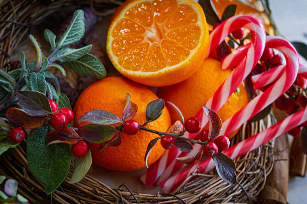 Festive Woven Basket of Oranges, Candy Canes, cotoneaster, and Pine Branches in Holiday Arrangement