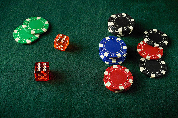 istock Red, green, blue, and black poker chips are neatly stacked alongside two brightly colored dice with winning numbers on a green felt table. Friends gather for a fun evening 2252239557