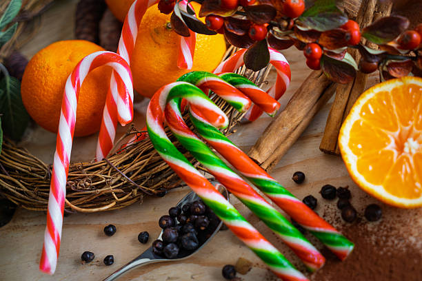 Candy canes and oranges arranged with cinnamon sticks and berries on rustic wooden table for holiday display