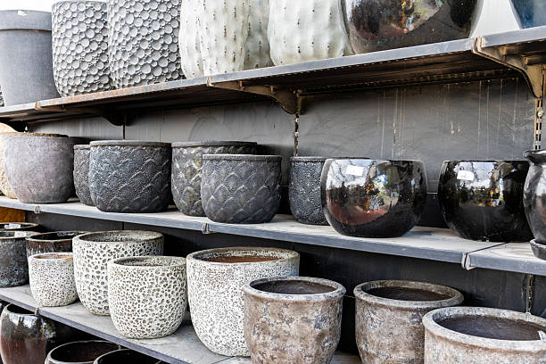 Rows of ceramic plant pots displayed on shelves inside a flower shop or garden center. Modern and minimalist home decor assortment featuring colorful and neutral ceramic planters, suitable for retail, interior design, gardening, lifestyle, and small business concepts. No people.