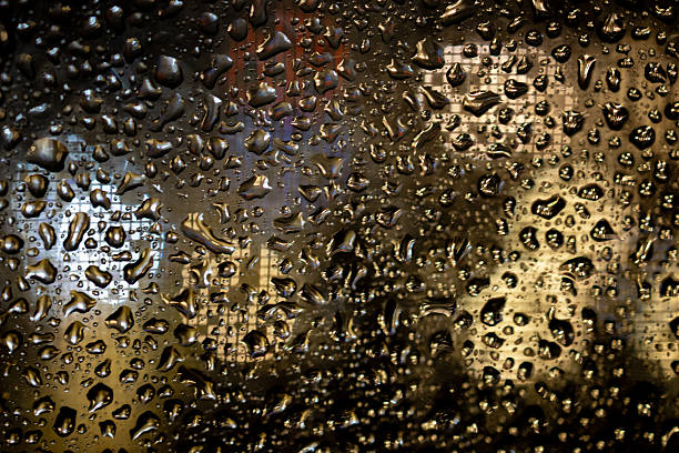 istock Raindrops on glass with blurred city lights background 2252244702