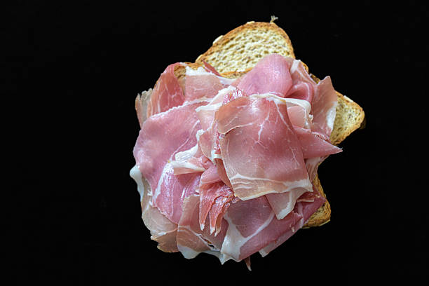 sandwich with prosciutto and tomato on wooden board