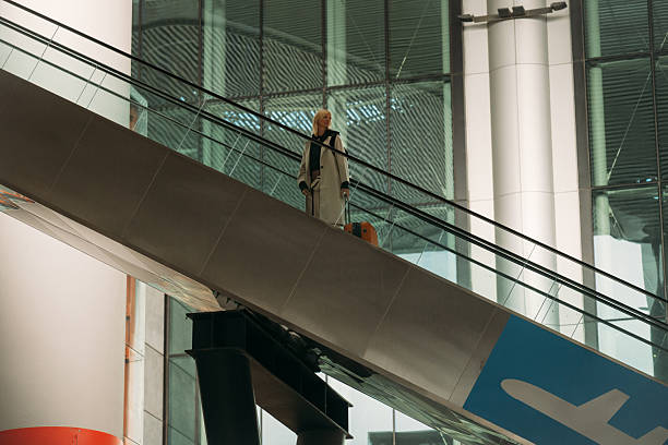 Traveler riding an escalator in a modern airport terminal with glass architecture.