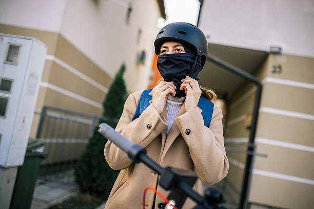 istock Girl puts scarf under helmet while riding scooter 2252253324