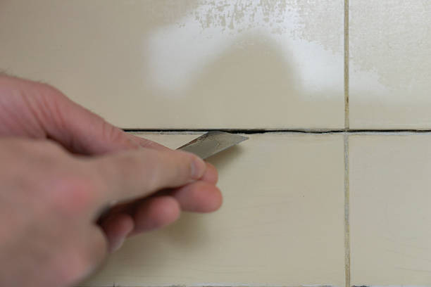 istock hands cleaning tile joints with metal spatula tool before grouting in bathroom or kitchen with copy space for banner design concept of home renovation repair construction 2252254468