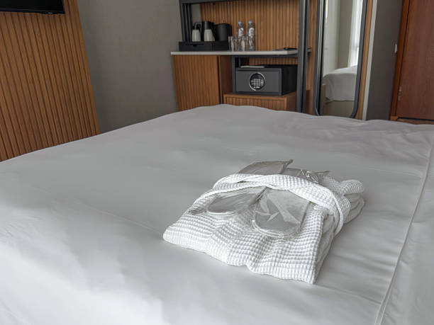 istock Hotel bedroom interior with neatly folded white bathrobe and slippers on clean bed, minimalist modern design, comfortable accommodation details, hospitality service, relaxation and travel stay concept 2252259018