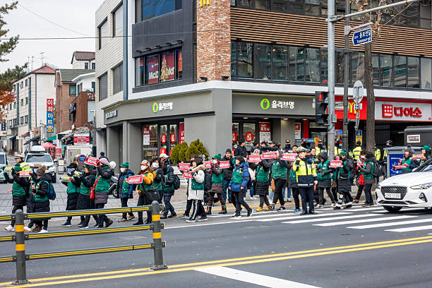 Seoul, S. Korea - Dec 3, 2019: March of Protesters beside a zebra crossing. A policeman keeping watch of the passing traffic for general safety.