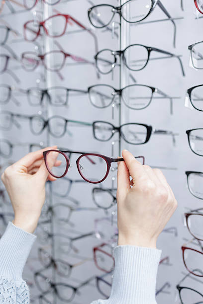 istock Close up hands holding eyeglass frame in optical shop choosing glasses from display 2252262777