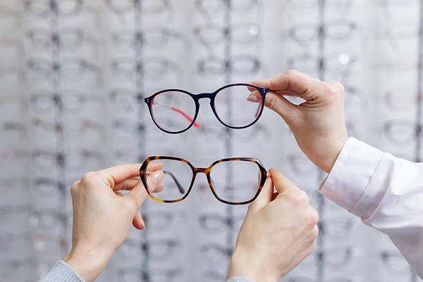 istock Hands comparing two eyeglass frames in optical store choosing eyewear for vision correction 2252262786