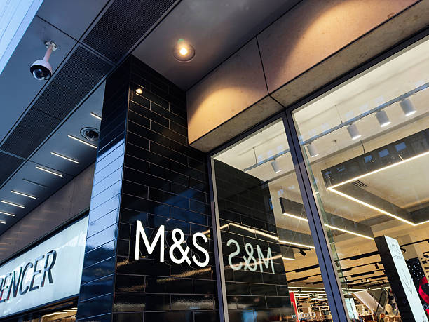 Manchester, UK - November 19, 2025: Exterior view of a contemporary M and S store in Manchester with glass facade and security camera