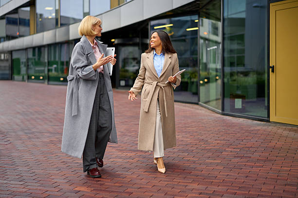 istock Diverse businesswomen walking, talking, collaborating outside modern office 2252266575