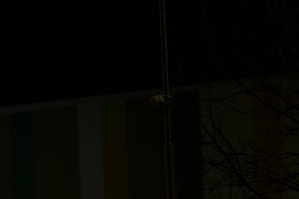 tall lamppost rising into black sky, solitary pole cutting through emptiness, subtle urban geometry and faint light reflections