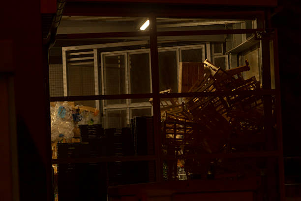 dimly lit storage room stacked pallets behind mesh partition, crates and plastic bins piled high, fluorescent fixture casting warm