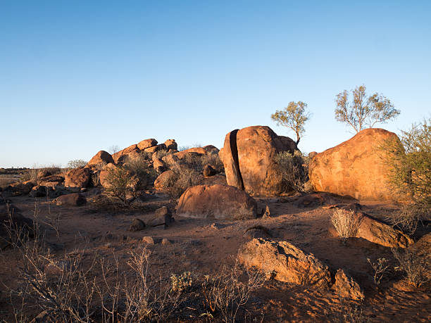 Large rocks in a rocky landscape with a blue sky and trees