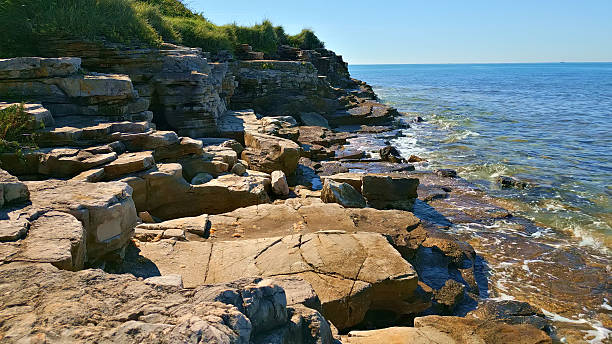 istock Rugged Coastline with Layered Rock Formations and Crashing Waves 2252275654