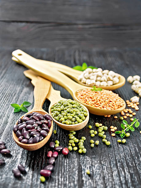 Lentils with chickpeas and beans in spoons on black board