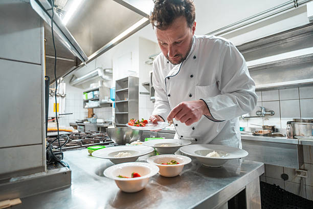 istock Professional Chef In White Uniform Carefully Plating Gourmet Dish Under Bright Kitchen Lighting 2252276594