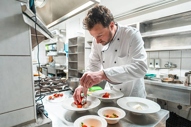 istock Chef in White Jacket Plating Gourmet Dishes in Professional Kitchen 2252276598