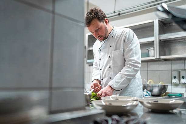istock Focused Male Chef Plating Gourmet Dish in a Modern Professional Kitchen 2252276602