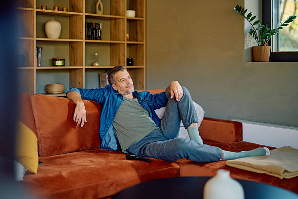 istock Man relaxing on sofa watching television in living room 2252276920