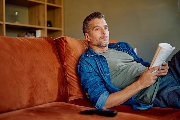 istock Man reading book relaxing on couch contemplating leisure time 2252277028