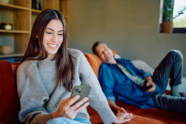 istock Couple relaxing at home, woman using phone, man smiling 2252277282