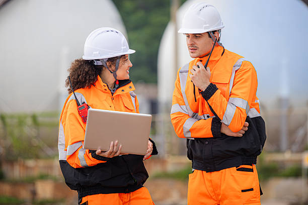 istock Team of Engineers Collaborating at Industrial Site with Storage Tanks, Industrial Workers Communicating and Using Laptop at Site, Engineers Conducting Operations at Oil Storage Field Industrial Site 2252277944