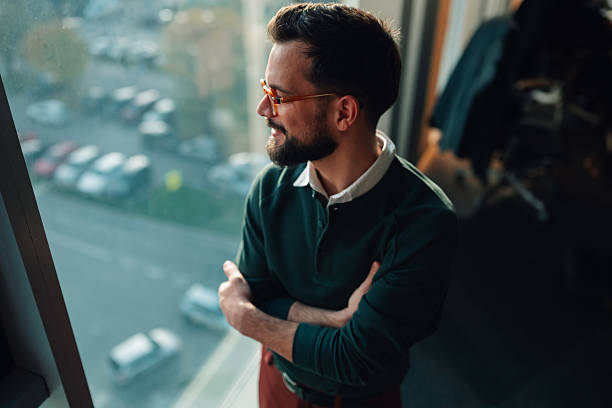 istock Stylish man contemplating urban view from office window 2252278263