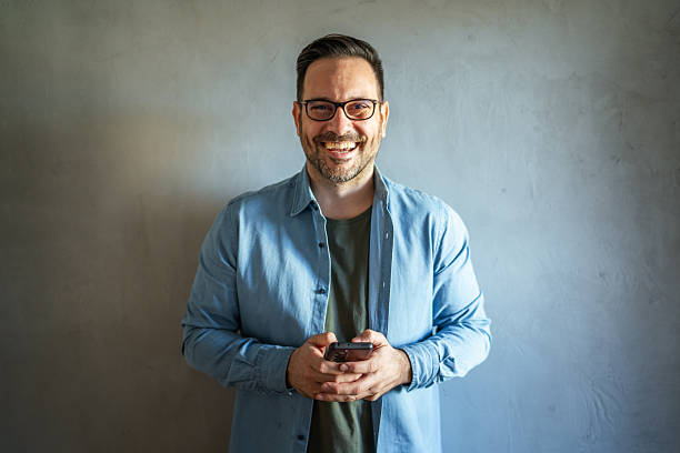 istock Happy man in eyeglasses holding a phone looking away 2252278669