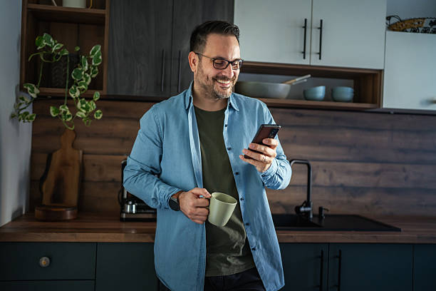 istock Man drinking coffee and checking phone in home office kitchen 2252278677
