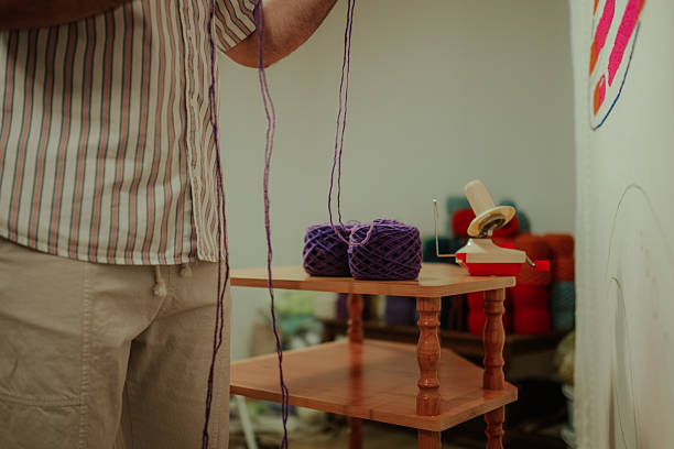 istock Man winding purple yarn using a winder 2252284372