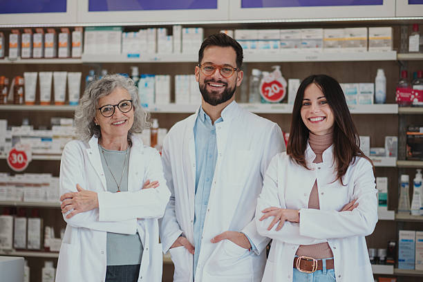 istock Smiling pharmacy team standing in front of shelves 2252284839