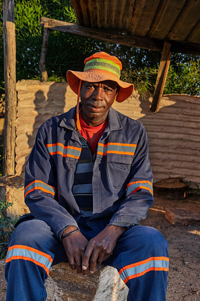istock single african men sitting outdoors on a stone bench at sunrise, setting has corrugated metal and wooden supports, Johannesburg 2252284970