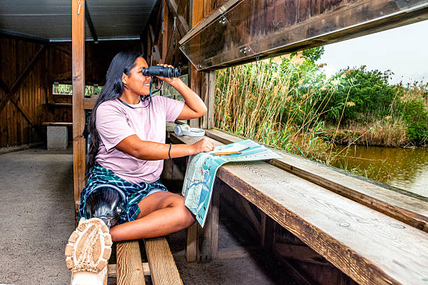 istock Young woman with prosthetic leg bird watching from hut 2252286642
