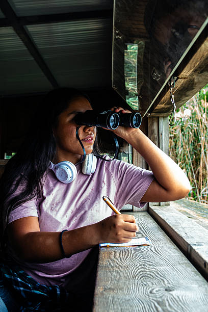 istock Young woman birdwatching with binoculars and writing observations 2252286794