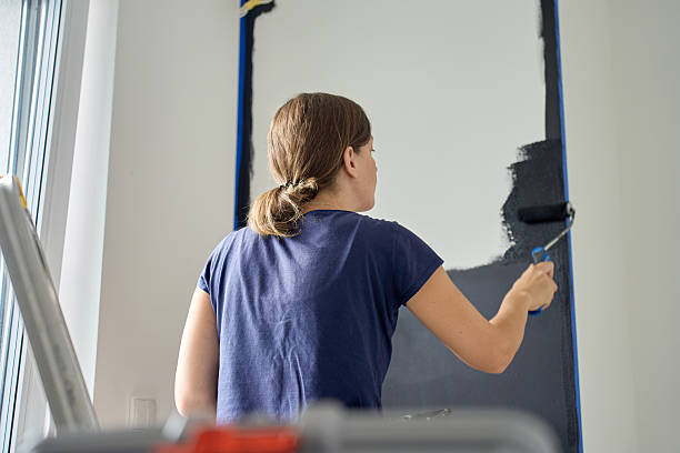 istock Woman painting interior wall with roller during home renovation 2252300181
