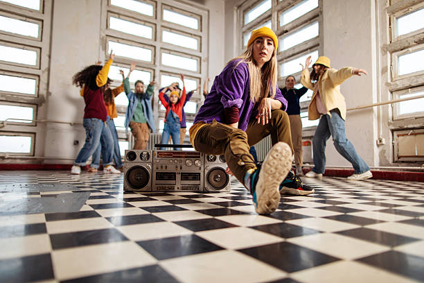 Group of five young women and men dancers dressed with urban clothes posing for a portrait in downtown.