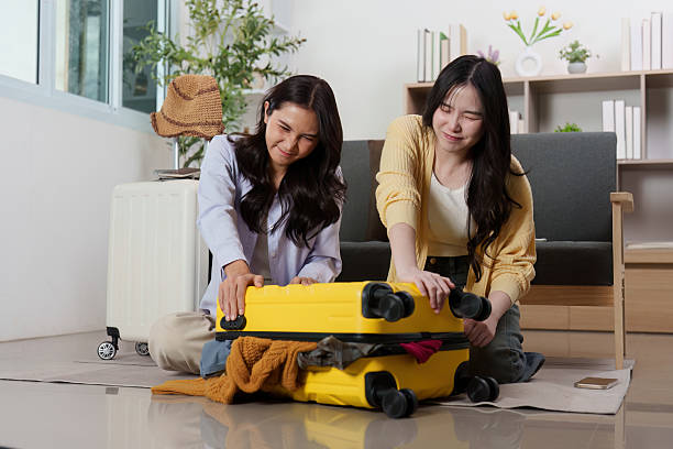 istock Travel Planning: Friends struggling to close their packed suitcase 2252302297