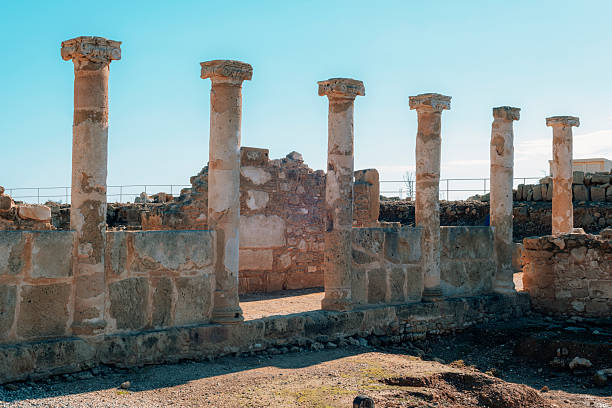Ancient stone columns ruins at archaeological site in Paphos, Cyprus. Remains of classical architecture under clear blue sky.